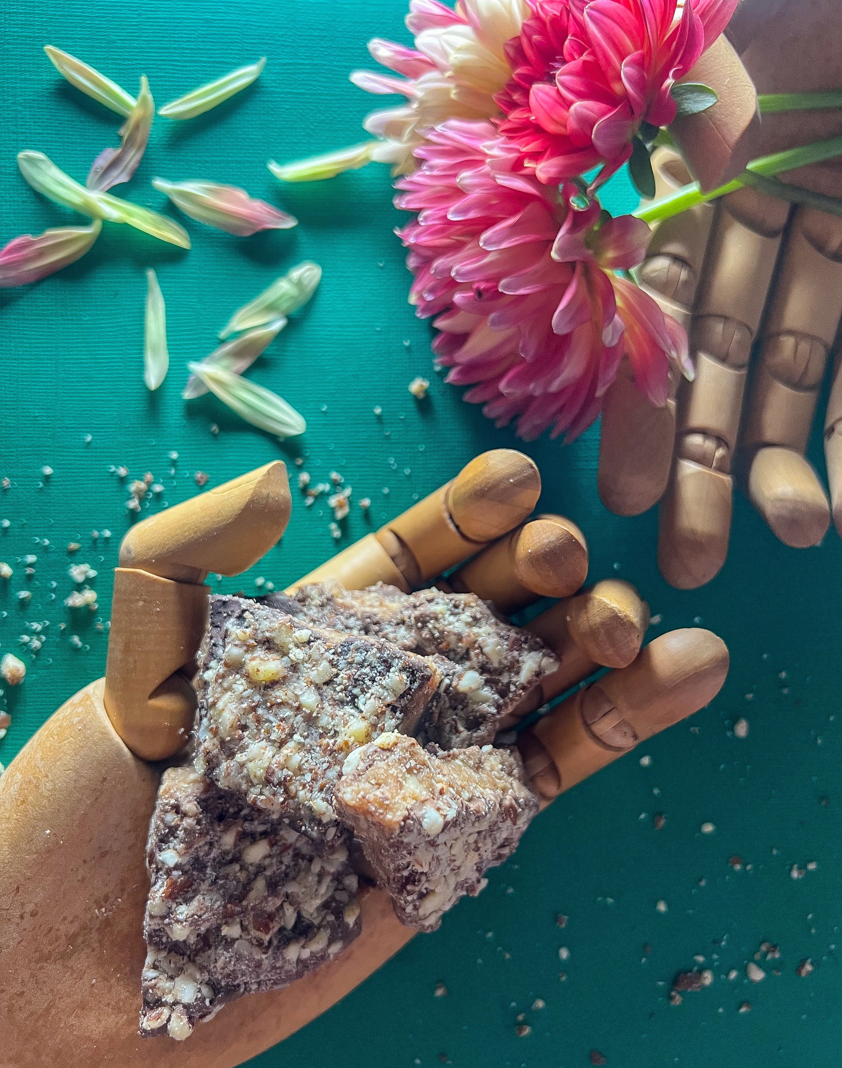 wooden hands holding toffee and some dahlia flowers